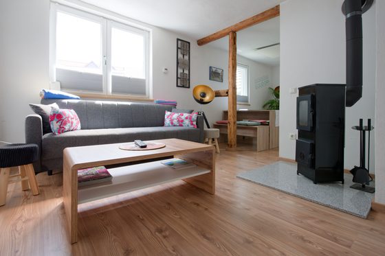 Wohnzimmer mit Schlafcouch, Couchtisch und Kaminofen, Blick zum Essbereich